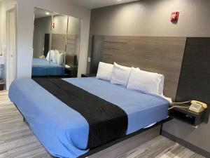 a large bed in a hotel room with a phone at Tweetys 9 Diamond Inn in Houston