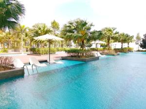 a pool with chairs and an umbrella and palm trees at POKO SUITE @ TIMURBAY in Kuantan