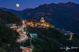 uma vista de uma cidade à noite com uma lua em Yunnan Homestaty em Ren'ai