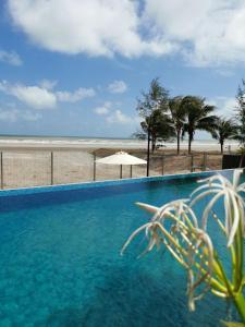 a blue swimming pool with a beach in the background at POKO SUITE @ TIMURBAY in Kuantan +3 photos