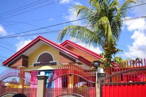 une maison avec une clôture rouge et un palmier dans l'établissement Modern House Staycation in Bacolod, à Bacolod