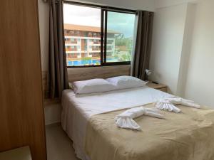 two beds in a room with a large window at Flat Extraordinário Beira Mar em Porto de Galinhas com pé na areia Cupe Beach Living in Porto De Galinhas