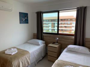 um quarto com 2 camas e uma grande janela em Flat Extraordinário Beira Mar em Porto de Galinhas com pé na areia Cupe Beach Living em Porto de Galinhas