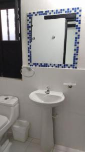 La salle de bains est pourvue d'un lavabo, d'un miroir et de toilettes. dans l'établissement Hotel Villa Paz, à Villa de Leyva