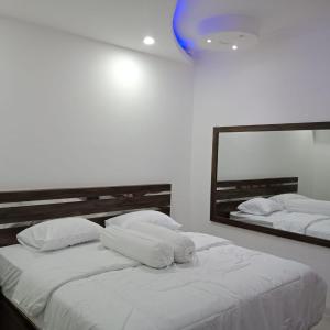 Budi Asih Guest house Syariah في Duku: غرفة نوم بسريرين بيض ومرآة