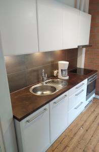 eine Küche mit weißen Schränken und einem Waschbecken in der Unterkunft Aia Guest Apartment in Pärnu