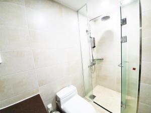 a bathroom with a toilet and a glass shower at Jeju Jungmun Ocean Blue Hotel in Seogwipo