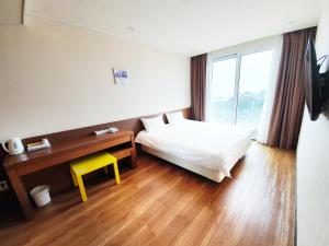 a hotel room with a bed and a yellow stool at Jeju Jungmun Ocean Blue Hotel in Seogwipo