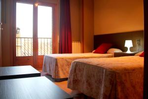 a hotel room with two beds and a window at Hostal Cafeteteria Goya in Barbastro