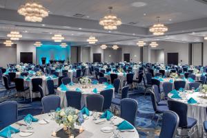 a banquet hall with tables and chairs and chandeliers at Crowne Plaza Boston - Woburn, an IHG Hotel in Woburn