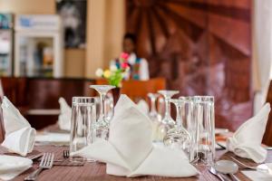uma mesa com copos de vinho e guardanapos em Marie's Royale Hotel em Kampala