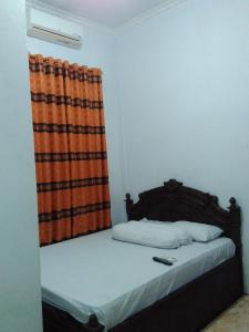 a bedroom with a bed with an orange curtain at Wisma Kahyangan in Baubau