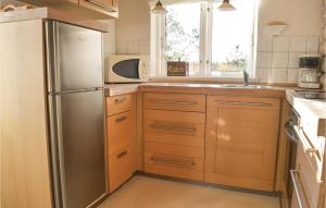 a kitchen with wooden cabinets and a stainless steel refrigerator at Two-Bedroom Holiday Home In Skjern in Halby