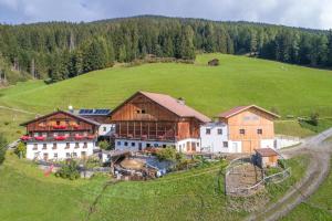 a group of buildings on a green hill with trees at Kerschbaumhof in San Candido