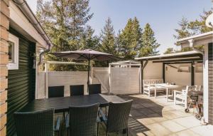 eine Terrasse mit Sonnenschirm und Tisch und Stühlen in der Unterkunft Oâsan in Bedegård