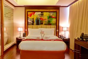 a bedroom with a large bed and a painting on the wall at Six Seasons Hotel in Dhaka