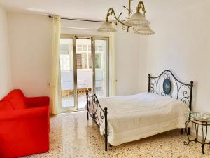 1 dormitorio con 1 cama y 1 silla roja en TAO SUN APARTMENT, en Giardini Naxos