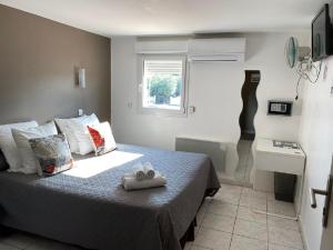 una camera da letto con un letto e un asciugamano sopra di LOGIS Hôtel La Chaumière a Marseillan