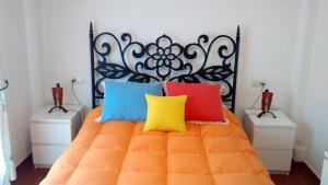 a bedroom with an orange bed with colorful pillows at Casa El Paseo in Arriate