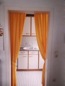 einen orangenen Vorhang in einer Küche mit Spüle in der Unterkunft Ferienwohnung Agnes in Nonnweiler