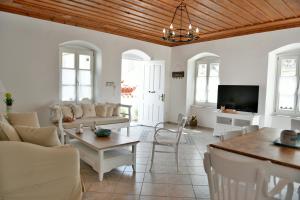 a living room with white furniture and a flat screen tv at Hydra's Pearl - White Pearl in Hydra