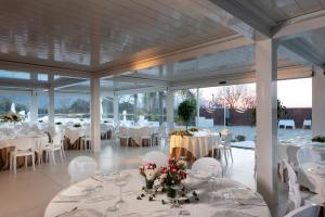 a banquet hall with white tables and white chairs at Likò Resort in Nocera Inferiore