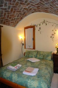 a bedroom with a green bed with a brick wall at B&B Il Libro Verde in Dolceacqua
