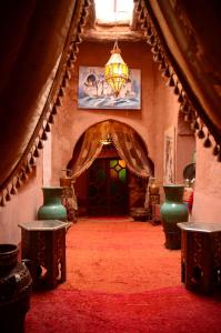 a living room with a chandelier and a red carpet at Kasbah du Peintre in Aït Ben Haddou