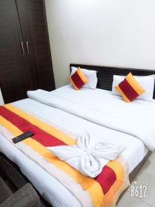 a hotel room with two beds with a towel on it at Kundan Plaza Jasola in New Delhi