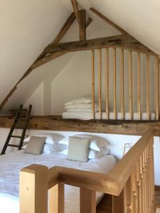 a loft bed with white sheets and pillows on it at WE Maison d'hôtes in Cassel