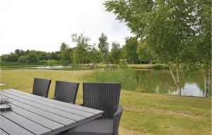 a picnic table with two chairs next to a lake at Holiday Home Dyrefolden Ringkøbing Ii in Ringkøbing