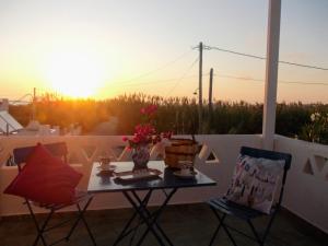 a table and chairs on a balcony with the sunset at Nyfes Traditional Boutique Vagelio in Skiros