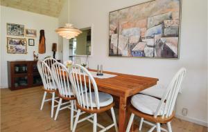 a dining room with a wooden table and white chairs at Amazing Home In Fan With Kitchen in Fanø