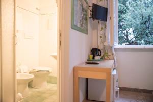 a bathroom with a toilet and a sink and a window at La Zattera Camere in San Vincenzo