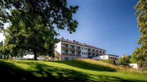 a building on top of a grassy hill with a tree at Hotel Parsberg in Puchheim