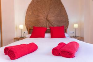 マラガにあるCITY CENTER NEXT TO THE BEACH 2 BEDROOMs APARTMENTのベッド1台(赤いタオル2枚、赤い枕2つ付)