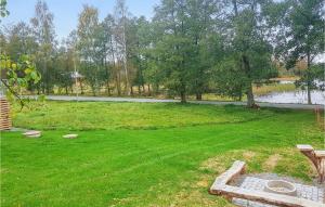 a large lawn with a pond in the background at Cozy Home In Lammhult With Sauna in Lammhult