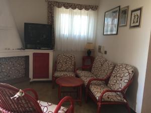 a living room with chairs and a tv at Casa Nuraghe Arvu in Cala Gonone