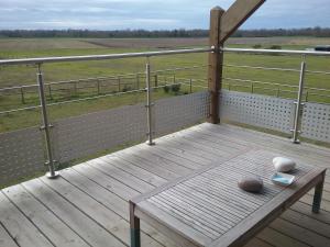 una terraza de madera con un banco en la parte superior de un campo en Maison bois en Germigny-des-Prés