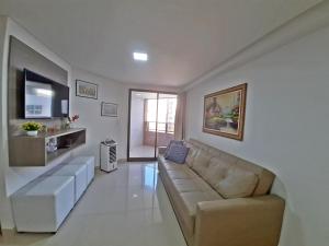 een woonkamer met een bank en een televisie bij GoldFlat in João Pessoa
