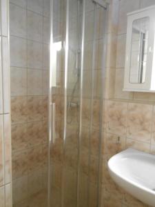 una ducha con una puerta de cristal junto a un lavabo en Villa Apolonija, en Zadar