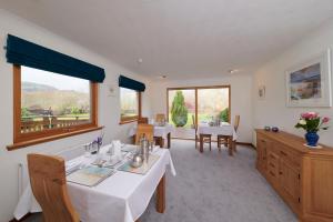 a dining room with two tables and two windows at Woodlands Bed & Breakfast in Drumnadrochit