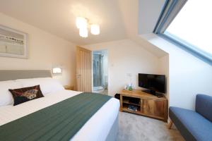 a bedroom with a bed and a tv and a couch at Woodlands Bed & Breakfast in Drumnadrochit