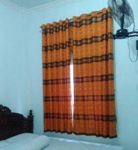 BaubauにあるWisma Kahyanganのベッド1台とファンが備わる客室内のカーテン