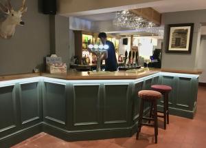 a man standing at a green bar with two stools at The White Hart Apartment Valley View in Alton