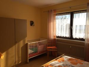 a baby bedroom with a crib and a window at Pension Nama in Spiegelau