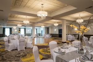 un salón de banquetes con mesas y sillas blancas y lámparas de araña en Crowne Plaza Chicago SW - Burr Ridge, an IHG Hotel, en Burr Ridge