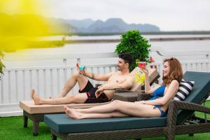 grupa ludzi siedzących na stole na patio pijących martini w obiekcie Madeline Cruises w Ha Long