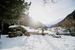 einen schneebedeckten Hof mit einem Haus und Bergen in der Unterkunft Alpenheim Simone in Sölden