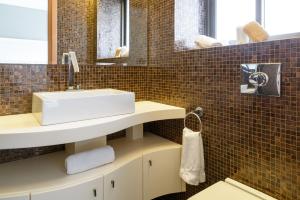 a bathroom with a white sink and brown tiles at Comfort 3BR Apt with Balcony near Beach by FeelHome in Tel Aviv